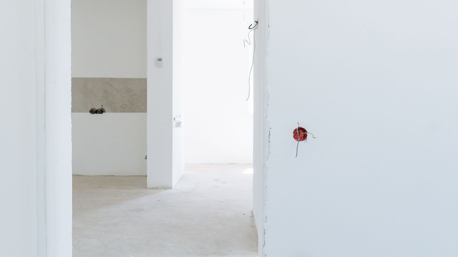An empty white room with several open doorways leading out of it