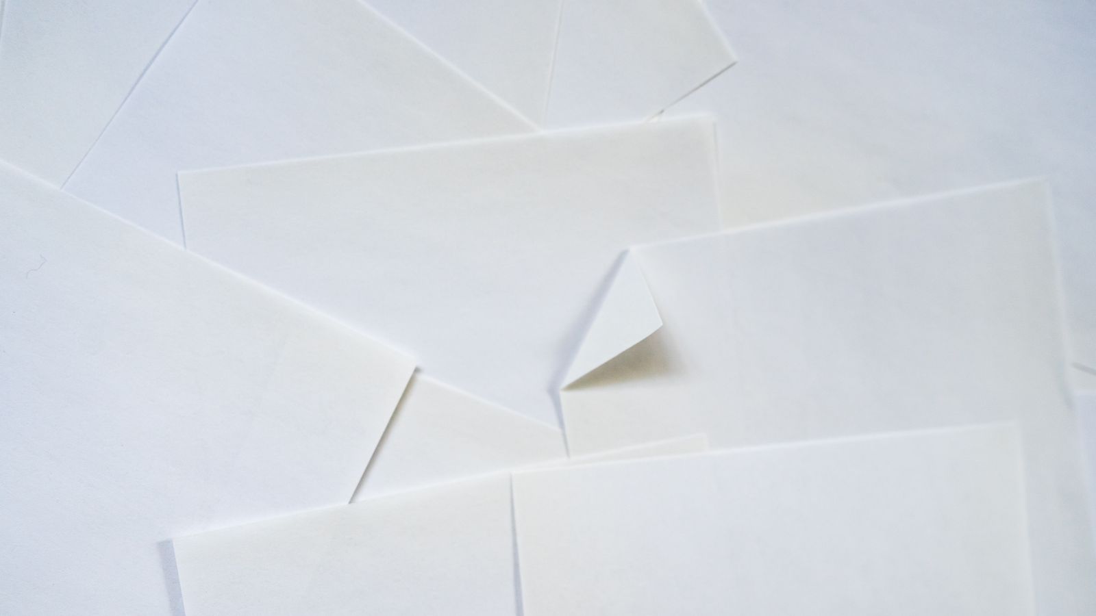 Plain white sheets of paper overlapping, the topmost hiding those beneath it